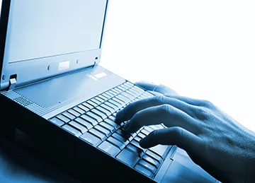 An image of a hand typing on a laptop computer.