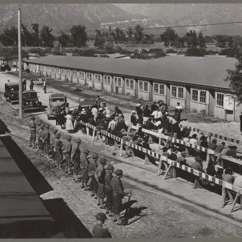 Japanese Americans are guarded at Santa Anita registration center. Uncleaned horse stables at the Southern California racetrack were used for temporary housing.