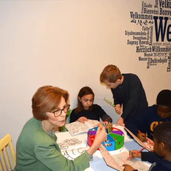 Chief Judge Rebecca R. Pallmeyer joins youngsters at a table with coloring books.