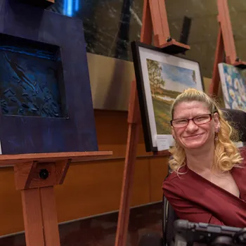 Artist Dorinda Tveit poses in front of her piece titled, "Breaking Through" during an art show at the Diana E. Murphy U.S. Courthouse in Minneapolis.