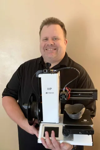 Software Developer Bryan King with the 3D printer he uses to make masks for first responders.