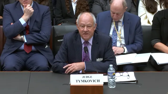 Judge Timothy M. Tymkovich sits behind a table and testifies during the hearing.