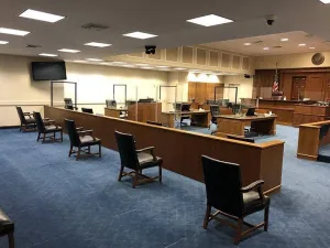 In a Baltimore courtroom, plexiglass divides the parties and court staff, and juror chairs are being kept at a safe social distance.